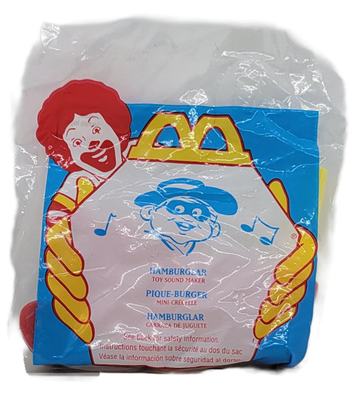 McDonald's Happy Meal Toy 1996 Toy Sound Maker Hamburglar, unopened plastic bag with colorful packaging featuring an illustration of Hamburglar and a hero mascot holding a hamburger.