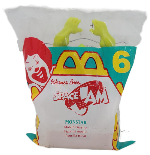 McDonald's Happy Meal Toy 1996 Warner Bros. Space Jam #6 Monstar, green plastic mobile figurine with hands raised inside a partially transparent plastic bag with colorful branding and character illustration.