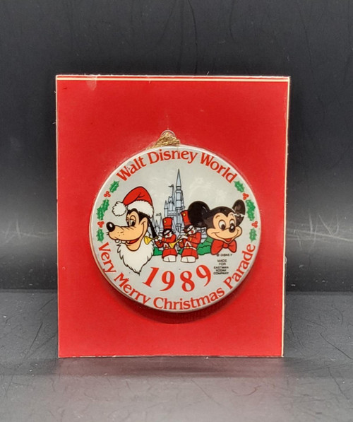 Disney Walt Disney World 1989 Very Merry Christmas Parade Ornament, vintage round Christmas ornament displayed on a red backing card, featuring Goofy in a Santa hat, Mickey Mouse, toy soldiers, and Cinderella Castle.