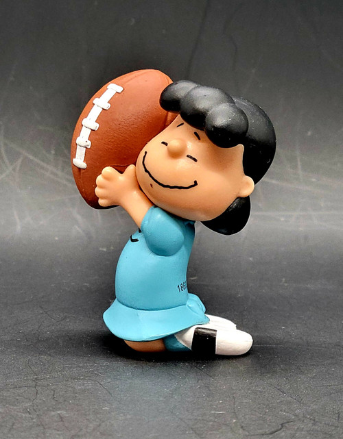 Peanuts Gang 2.25-inch tall mini figure of Lucy Van Pelt holding a football. The mini figures were sold in surprise eggs. Lucille "Lucy" Van Pelt is a fictional character in the syndicated comic strip Peanuts, written and drawn by Charles Schulz. She is the older sister of Linus and Rerun.