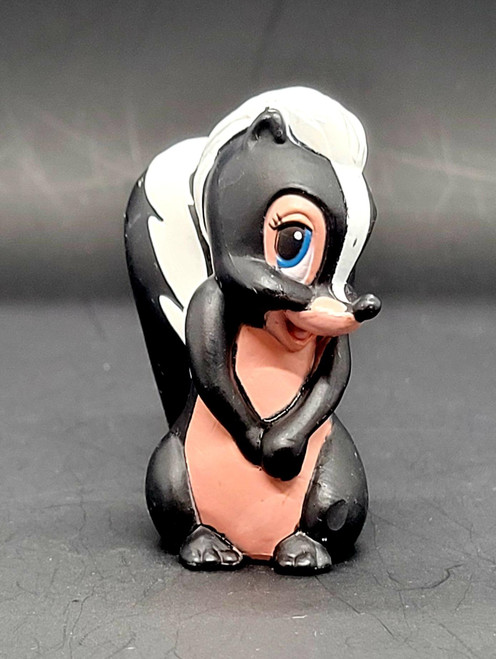 Disney's Bambi Flower the Skunk 2.25" PVC Figure, cute black-and-white skunk figurine with blue eyes and pink belly posed sitting against a gray background