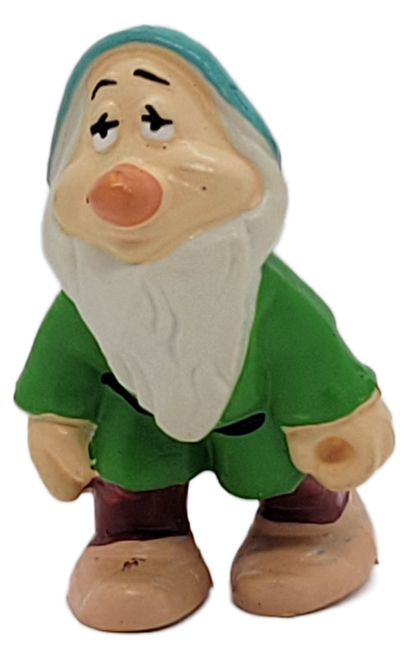 This charming vintage figure depicts Sleepy, one of Snow White’s beloved Seven Dwarfs, with his unmistakable drowsy expression, drooping eyelids, long white beard, and relaxed pose. He is dressed in a green tunic, turquoise-blue cap, burgundy pants, black belt, and tan shoes, capturing the distinctive personality of the famously tired dwarf.