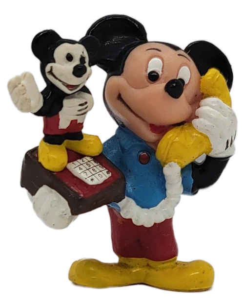 Vintage 1980s Applause Mickey Mouse Telephone PVC Figurine. This colorful collectible depicts Mickey Mouse talking on a yellow telephone while carrying a novelty telephone featuring a miniature Mickey Mouse figure standing beside the keypad.