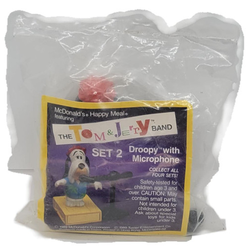 McDonald's Happy Meal Toy 1990 The Tom & Jerry Band Set 2 Droopy With Microphone, vintage toy sealed in a clear plastic bag with its original yellow-bordered packaging showing Droopy holding a microphone on a wooden platform.