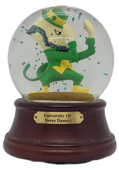 PJML Vintage 1999 PJML Notre Dame Musical Snow Globe – Fighting Irish Leprechaun, vintage snow globe featuring a green-and-gold leprechaun surrounded by floating confetti, on a dark wooden base with a University of Notre Dame plaque.