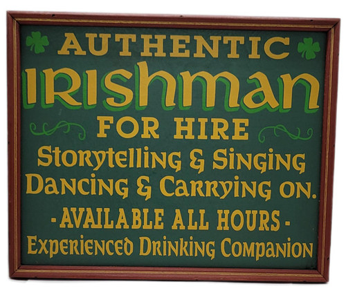 Draben's Toyland 1930s “Authentic Irishman for Hire” Painted Wooden Sign with Red Frame, vintage-style dark green sign with a reddish wooden frame, gold lettering advertising an authentic Irishman for hire for storytelling, singing, dancing, and companionship, decorated with green shamrocks.