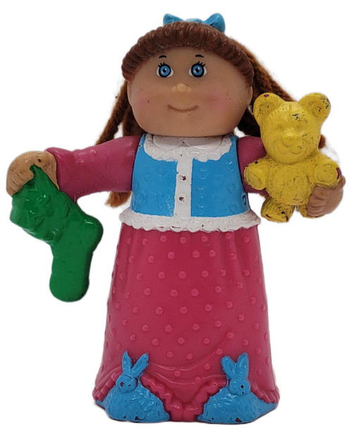 McDonald's 1992 Happy Meal Cabbage Patch Kids Lindsey Elizabeth Holiday Dreamer 3-inch Figure, front view of a brown-haired doll in a pink and blue dress holding a green toy and yellow teddy bear, with blue bunny details at the hem.