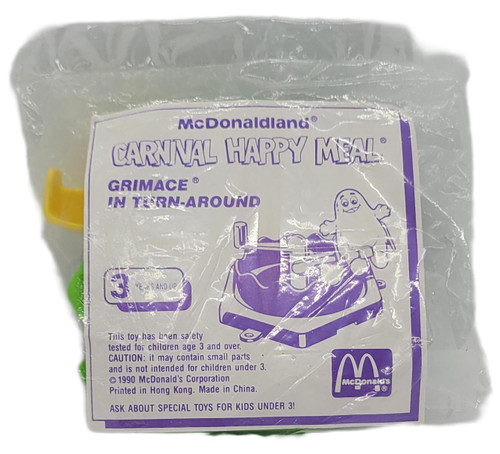 1990 McDonald's McDonaldland Carnival Happy Meal Grimace Turn-Around Toy Sealed, vintage toy in its original clear sealed packaging with a purple Grimace turn-around illustration and printed McDonaldland Carnival Happy Meal label.