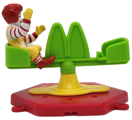 1990 McDonald's McDonaldland Carnival Happy Meal Ronald on Carousel Toy, vintage Ronald McDonald figure seated on a bright green carousel ride with yellow support and red base, shown against a white background.