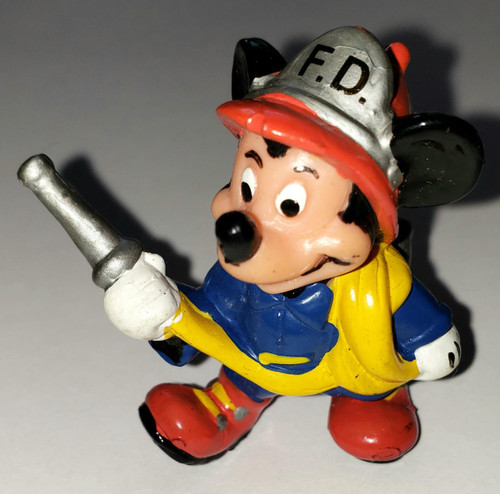 Disney Mickey Mouse As Fireman PVC Toy Figure, animated Mickey Mouse dressed as a fireman with a fire hat marked F.D., holding a silver fire hose, wearing a blue shirt, yellow suspenders, red shoes, and a yellow backpack.