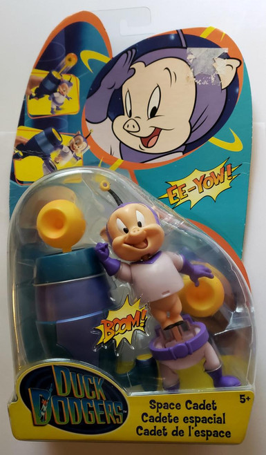 Warner Bros. Duck Dodgers Space Cadet Action Figure, plastic toy figure of a cartoon pig in space suit with a purple helmet and gloves, standing next to a blue and yellow spaceship with a yellow antenna, in colorful packaging with cartoon character images and comic-style text.