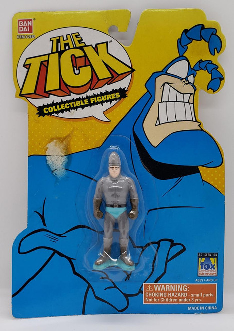 BAN DAI BANDAI The Tick - Human Bullet Collectible Figure, a small toy figure of The Tick superhero in a gray costume, displayed in blister packaging with colorful comic-style background and branding.