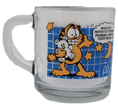 Garfield Vintage 1978 McDonald's Garfield Coffee Cup with cartoon Garfield holding a teddy bear and a quote about mornings, featuring stars and a blue grid background.