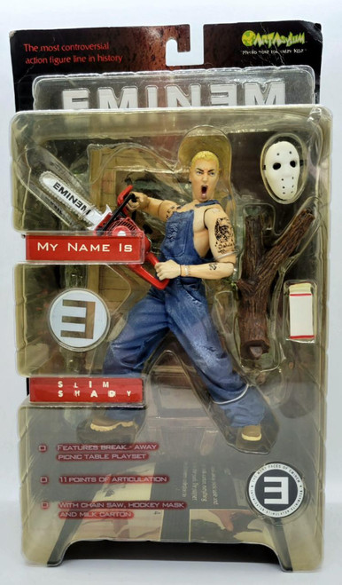 Art Asylum Eminem "Slim Shady" Action Figure in packaging, featuring a detailed figure holding a chainsaw, with accessories including a hockey mask, log, and milk carton.