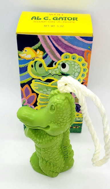 AVON Vintage AVON Al E. Gator Soap-On-A-Rope, green crocodile-shaped soap on a white rope with packaging in the background featuring colorful cartoon illustrations.