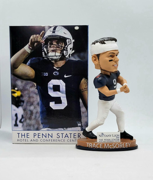 Legends Penn State Trace McSorley Bobblehead, collectible figurine of Penn State football player Trace McSorley in uniform with black eye paint, standing on a brown base with his name, positioned next to packaging featuring an action shot of Trace McSorley in Penn State jersey.