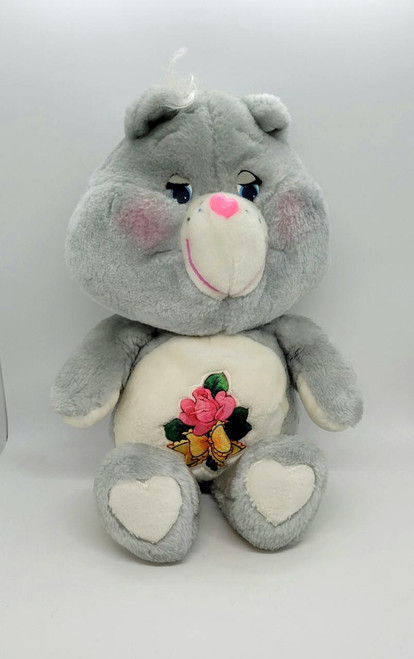 Care Bears - Grams Bear, a plush grey teddy bear with a embroidered flower and leaf design on its belly.