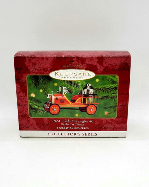 Hallmark Keepsake Ornament: Kiddie Car Classics - 1924 Toledo Fire Engine #6, collectible Christmas ornament featuring a detailed miniature of a vintage red fire engine with gold and black accents, set against a green festive background with holiday ornaments.