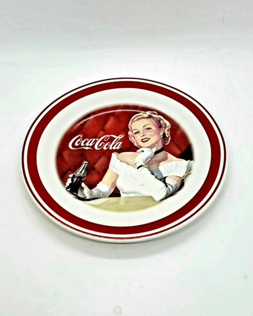 Coca-Cola 7-inch Plate, vintage style plate featuring an illustration of Marilyn Monroe holding a Coca-Cola bottle, with a red and white background and the Coca-Cola logo.
