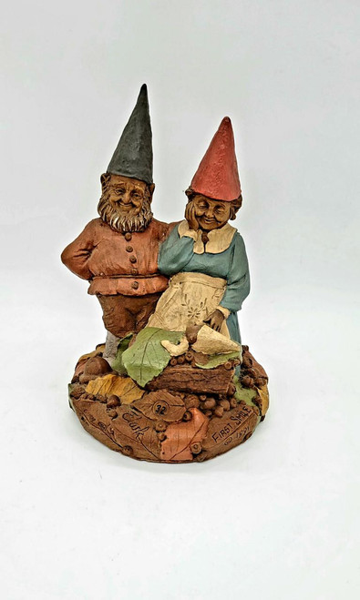 Cairn Studio, LTD Tom Clark Gnomes - First Smile figurine featuring two cheerful gnomes with smiling faces, wearing pointed hats and rustic clothing, displayed on a detailed base that includes natural elements like leaves and bark.