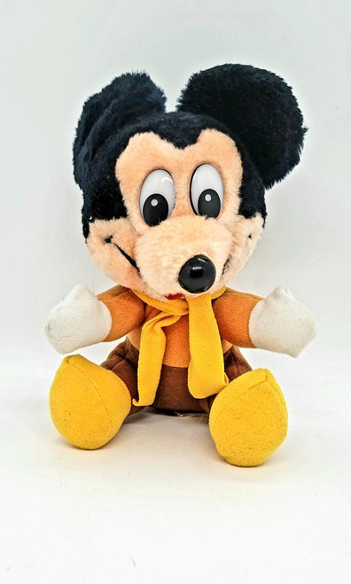 Disney's Mickey's Christmas Carol Mickey Mouse Plush, a soft and cuddly stuffed toy featuring Mickey Mouse dressed as Ebenezer Scrooge with a warm yellow scarf, brown coat, and yellow shoes.