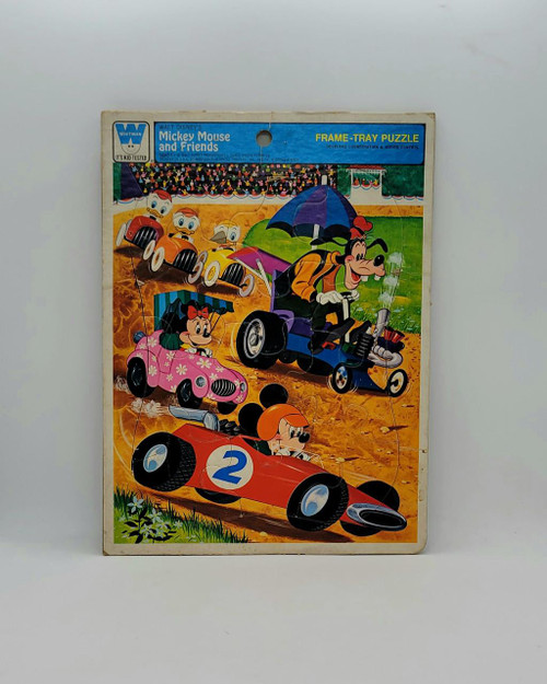 Disney Mickey Mouse And Friends Racing Frame-Tray Puzzle, colorful illustration of Mickey Mouse and friends racing go-karts on a dirt track with a crowd in the background.