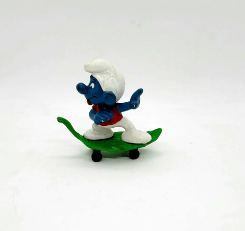 Smurfs Vintage PEYO 4.0204 Skateboard Smurf (Leaf Variant) PVC Figure, collectible blue Smurf figurine with white hat on a green skateboard with black wheels.