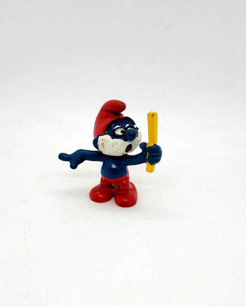 Smurfs Vintage 1981 Schleich 4.0224 Teacher Papa Smurf PVC Figure, a small figurine of Papa Smurf with glasses, holding a yellow ruler, wearing a red hat and pants, and a white beard.