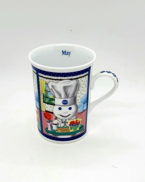Pillsbury Doughboy Fine Porcelain Collector Mug, featuring a colorful design of the Doughboy wearing a chef's hat with a Mother's Day breakfast theme on May.
