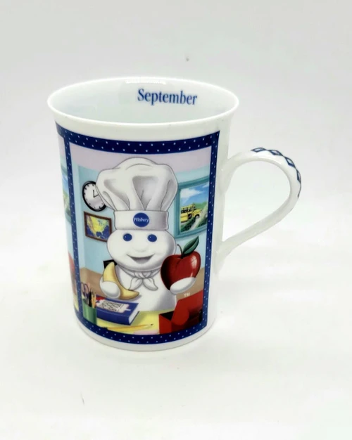 Pillsbury Doughboy Fine Porcelain Collector Mug, September Back To School edition with a colorful classroom scene and the Doughboy dressed as a chef holding an apple.