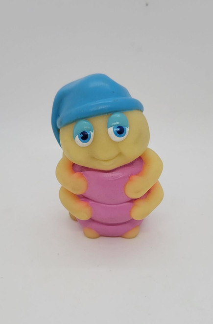 Hasbro Glo Friends Snugbug Mini Figure, a small toy with a cute yellow face, blue hat, and pink body with arms hugging the body, made of glow-in-the-dark material.