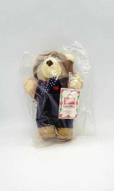 Furskins Wendy's FURSKINS Bears - Farrell, a plush bear toy dressed in a black outfit with a blue polka dot bow tie, packaged in clear plastic wrapping.