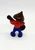 Hershey's 1984 Hershkins Playing Guitar PVC Toy Figure, colorful toy figure of a character playing guitar with a brown head, red shirt, blue pants, and black musical instrument, vintage collectible