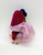 Liddle Kiddle Vintage 1968 Greta Grape Liddle Kiddle Doll, doll with pink hair, wearing a purple dress and a red hat, with black shoes, on a white background.