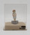 Emma Bebe Porcelain 1928 Emma Bebe Hat or Coat Stick Pin, vintage porcelain figurine of a girl in a pink hat and coat holding a small animal, displayed in a clear case with label.