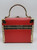 Delill Vintage Box/Train Purse -Red, a retro-style handbag designed to resemble a vintage train or box, with a red exterior and metallic gold accents and handle for an elegant look.