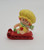 Strawberry Shortcake Strawberryland Miniatures Apple Dumplin On Sled, a small decorative figurine of a girl with red hair, yellow hat, and striped accessories riding a red sled.
