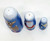 Babooshkah Rudolph The Red-Nosed Reindeer 50th Anniversary Wood Nesting Doll Set, featuring three nested wooden dolls painted with festive Christmas characters including Rudolph, Santa Claus, and a girl elf, in a blue color scheme.