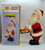 Jamina Vintage Battery Operated Drumming Happy Santa, a battery-powered Santa Claus figurine playing drums, made in Korea, with its packaging showing the product image and branding.