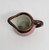 Pavelco hand painted 2-inch tall ceramic creamer with handle.  The creamer is pink with bronze colored trim.  The sides have hand painted cottages with trees.