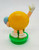 M&M's Candy Topper - Yellow M&M holding Easter Egg, cartoon-style toy figurine.