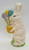 Midwest of Cannon Falls Spring Rabbit Easter Bunny with Flowers sculpture by Teena Flanner, ceramic bunny holding colorful flowers with green grass base