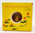 Product R. L. Alberts & Son Vintage 1960's Happy Easter Panorama Egg, still sealed, with a yellow box featuring a round window showing the egg inside, decorated with orange flowers and green grass illustration.