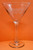 Hershey Entertainment Hershey Lodge Martini Glass, clear glass martini glass with Hershey Lodge logo engraved, against an orange background.