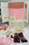 Vogue Dolls The World of Ginny Wardrobe and Accessories Playset, a miniature white doll wardrobe with pink interior, decorated drawers, hooks, mirror, and clothing accessories including a hat, scarf, fabric, and shoes.