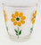 Hazel Atlas Vintage Hazel Atlas Orange Daisy Sour Cream Half Pint Glass, with colorful flower design featuring yellow petals, green leaves, and a green center on a clear glass background.