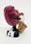 The California Raisins - 1987 Sax the Raisin PVC Toy Figure, a vintage collectible figurine of a raisin character playing a saxophone, with a maroon body, black and white shoes, and a gold saxophone, set against a plain white background.