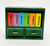 Calico Critters EPOCH 1985 Calico Critters - Bookcase with Books, a miniature green wooden bookcase with two small drawers and colorful books on top.