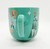 Disney Mickey & Minnie Mouse Joy Christmas Mug, teal ceramic mug featuring festive holiday graphics and character illustrations.