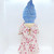 Unbranded Antique Composition 13.5" Blonde Hair Girl Doll, vintage doll with blonde hair, dressed in a floral pink and white outfit with a knot at the neckline, and wearing a blue fabric hat.